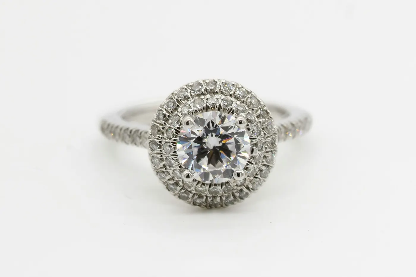 A double halo engagement ring in white metal, round brilliant centre stone circled by two rows of smaller diamonds