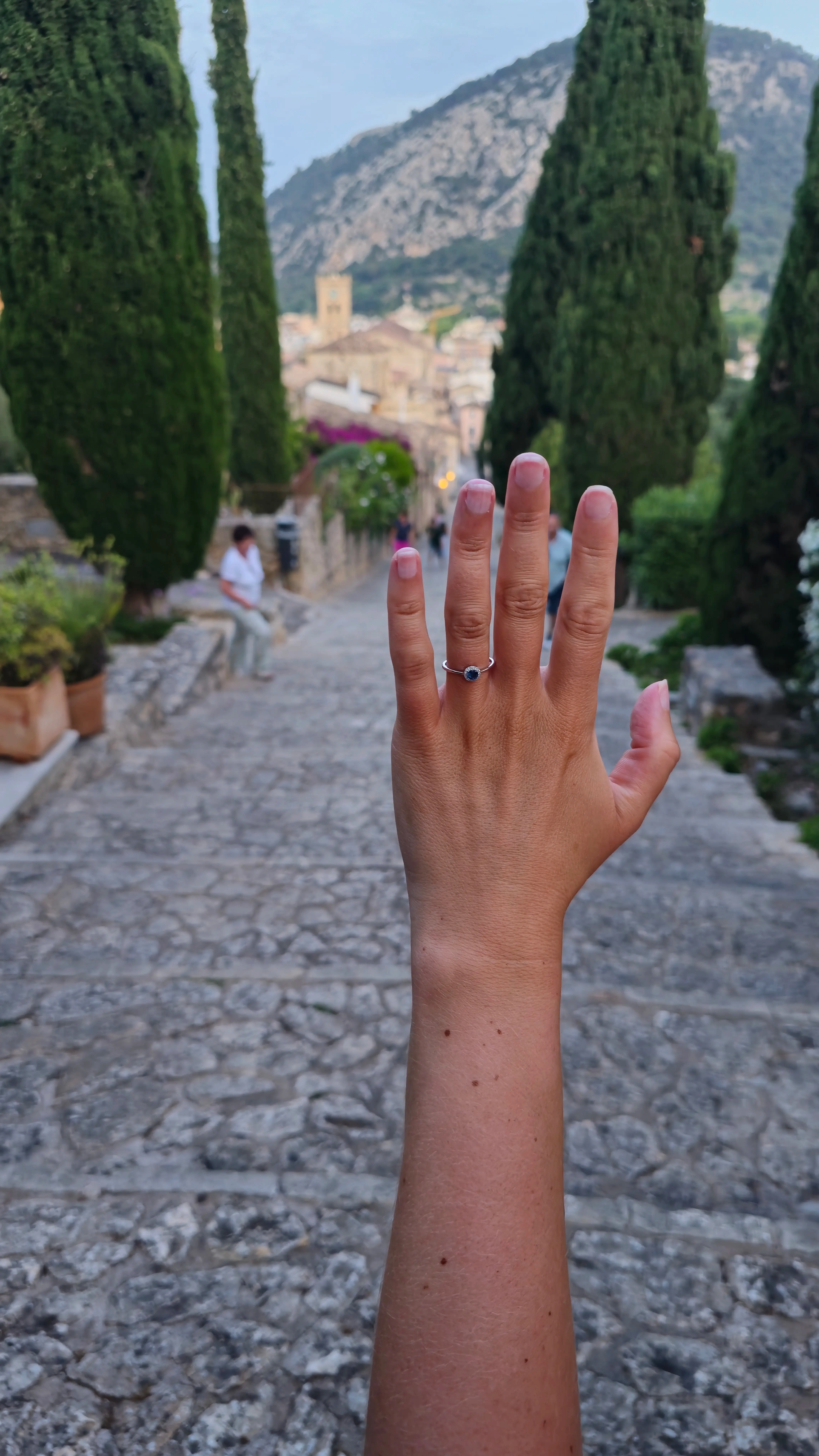 A sapphire ring held against the blue Mediterranean sea and sky from the Calvari Steps, Pollença, Mallorca