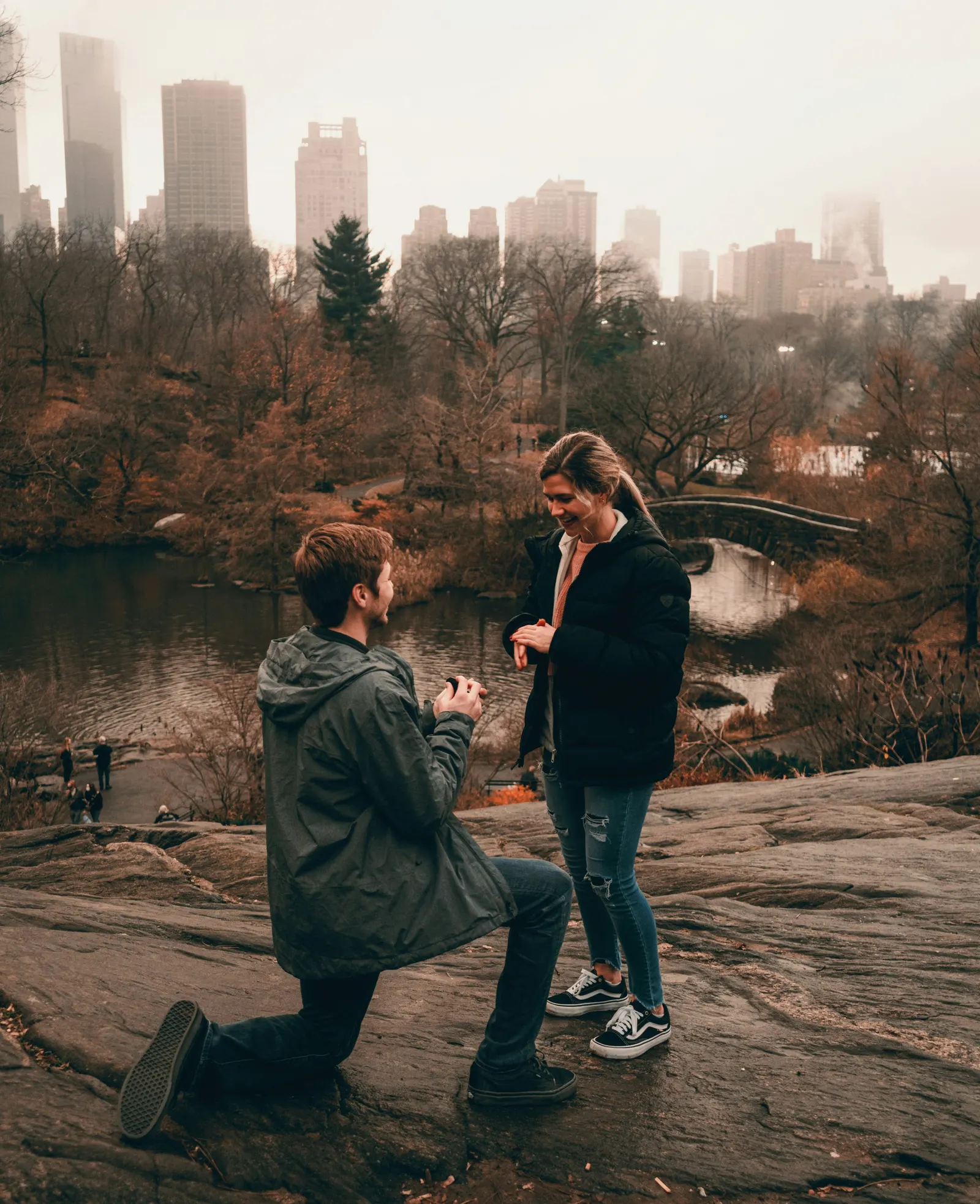 A proposal on a rocky outcrop in Central Park, New York, misty skyline behind